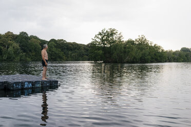 Senior man standing on raft in a lake - GUSF01805