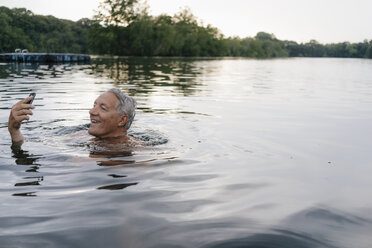 Senior man using cell phone in a lake - GUSF01807