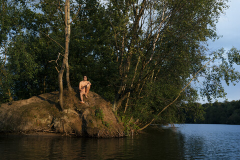 Mann sitzt auf einer Insel in einem See, lizenzfreies Stockfoto