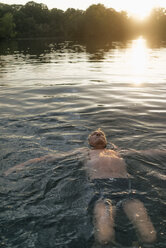 Älterer Mann schwimmt in einem See bei Sonnenuntergang - GUSF01820