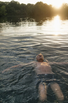 Älterer Mann schwimmt in einem See bei Sonnenuntergang - GUSF01820