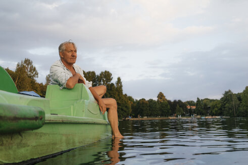 Älterer Mann sitzt auf einem Paddelboot auf einem See - GUSF01828