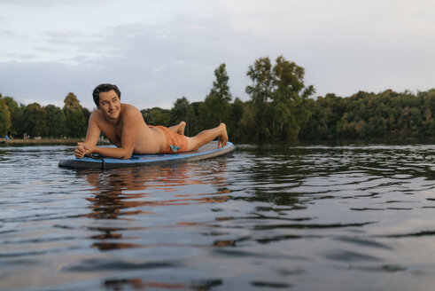 Mann liegend auf SUP-Board auf einem See - GUSF01829