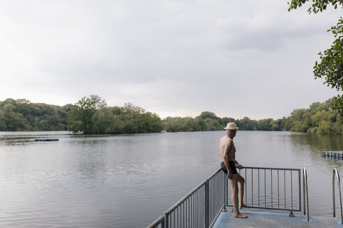 Älterer Mann mit Strohhut steht an einem See - GUSF01832
