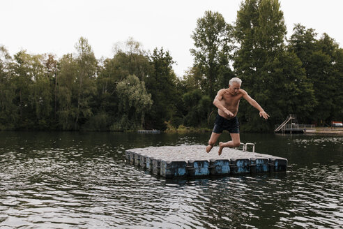 Älterer Mann springt von einem Floß in einen See - GUSF01836