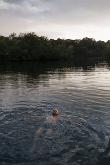 Älterer Mann schwimmt in einem See bei Sonnenuntergang - GUSF01851