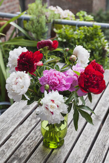 Strauß weißer, roter und rosa Pfingstrosen in Vase auf Gartentisch - GWF05793