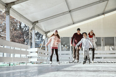 Family with two kids ice skating on the ice rink - ZEDF01787