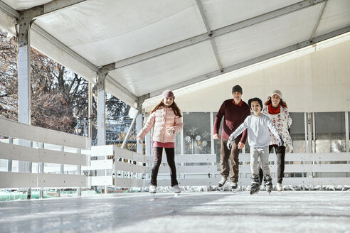 Familie mit zwei Kindern beim Schlittschuhlaufen auf der Eislaufbahn - ZEDF01787