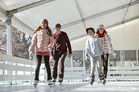 Familie mit zwei Kindern beim Schlittschuhlaufen auf der Eislaufbahn, lizenzfreies Stockfoto