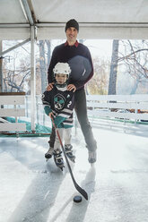 Father and son on the ice rink, boy playing ice hockey - ZEDF01800