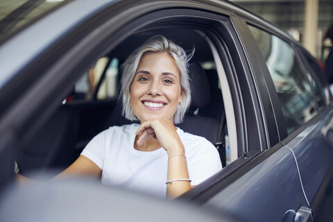 Junge Frau sitzt in ihrem Auto, lizenzfreies Stockfoto