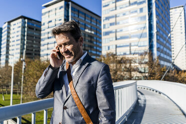 Businessman walking on a bridge, talking on the phone - GIOF05564