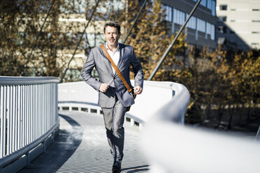 Businessman wearing full suit, running on a bridge - GIOF05567