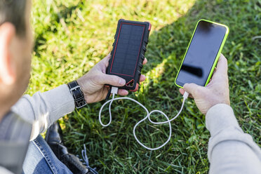 Geschäftsmann lädt sein Smartphone mit einer Solarstrombank auf - GIOF05608