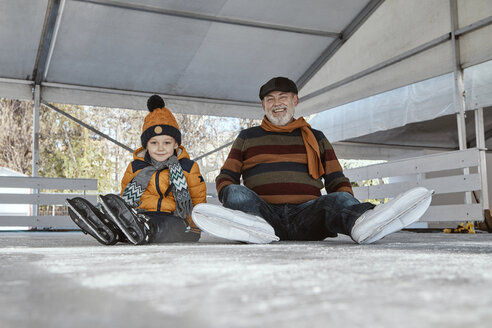 Großvater und Enkel auf der Eislaufbahn, auf dem Eis sitzend - ZEDF01813