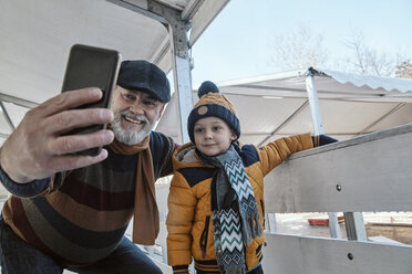 Grandfather and grandson on the ice rink, taking selfies - ZEDF01815