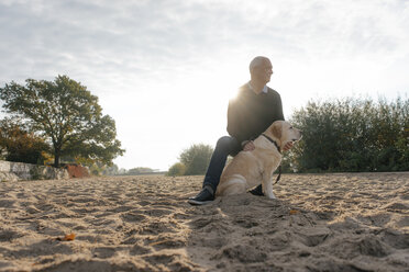 Deutschland, Hamburg, älterer Mann mit Hund am Strand am Elbufer - JOSF02876