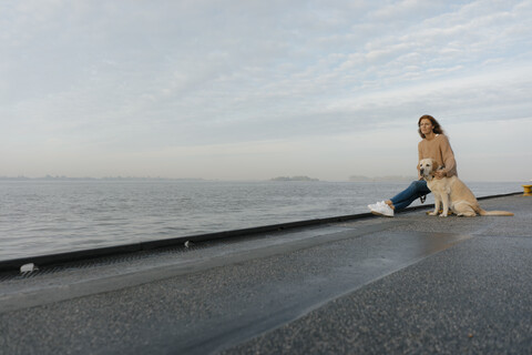 Deutschland, Hamburg, Frau mit Hund auf Pier am Elbufer, lizenzfreies Stockfoto