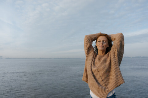 Deutschland, Hamburg, Frau mit geschlossenen Augen am Elbufer stehend, lizenzfreies Stockfoto