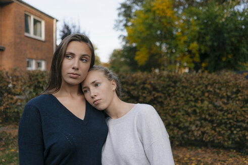 Two affectionate thoughtful teenage girls in garden - JOSF02892