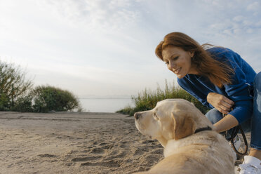 Germany, Hamburg, woman with dog on beach at the Elbe shore - JOSF02899