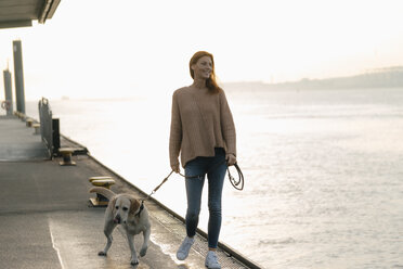 Germany, Hamburg, woman walking with dog on pier at the Elbe shore - JOSF02902