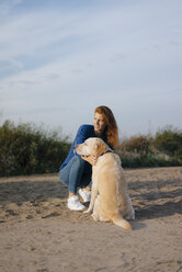 Germany, Hamburg, woman with dog on beach at the Elbe shore - JOSF02905