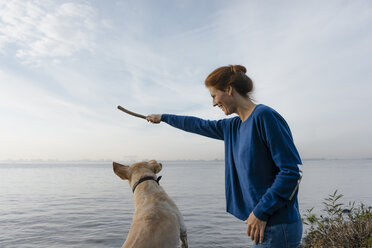 Deutschland, Hamburg, glückliche Frau spielt mit Hund am Strand am Elbufer - JOSF02907