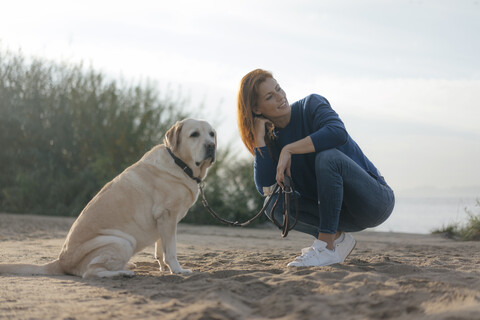 Deutschland, Hamburg, Frau mit Hund am Strand am Elbufer, lizenzfreies Stockfoto