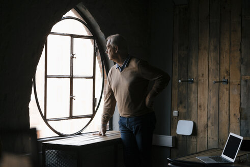 Serious senior businessman looking out of window in office - JOSF02913