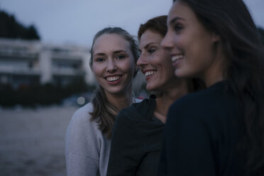 Deutschland, Hamburg, glückliche Mutter mit zwei Teenager-Mädchen am Strand am Elbufer am Abend - JOSF02923