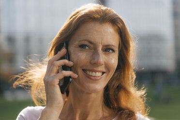 Portrait of smiling businesswoman on cell phone outdoors in the city - JOSF02935