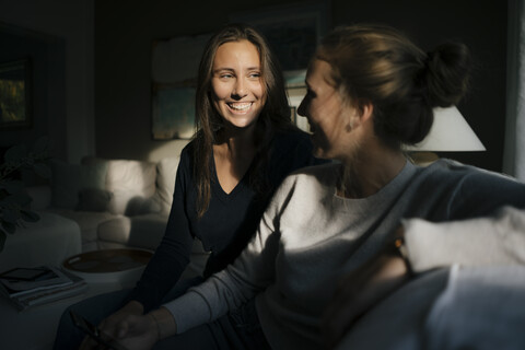 Two happy teenage girls with cell phone sitting on couch at home stock photo