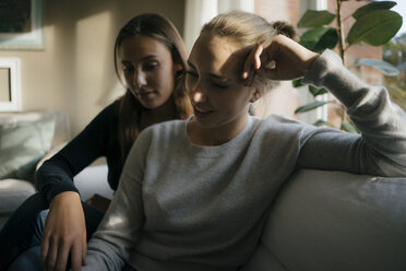 Zwei Mädchen im Teenageralter sitzen auf der Couch zu Hause - JOSF02943