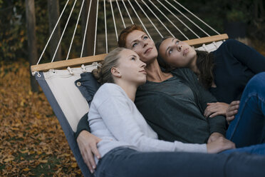 Mutter mit zwei Mädchen im Teenageralter in der Hängematte liegend im Garten im Herbst - JOSF02961