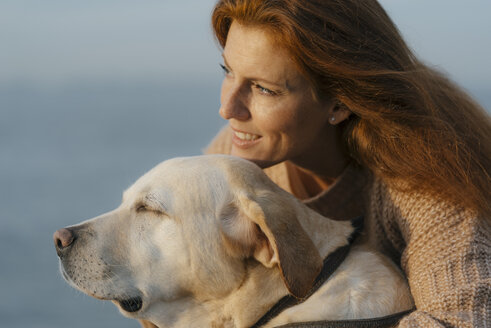 Germany, Hamburg, happy woman cuddling with dog at the Elbe shore - JOSF02984