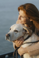 Germany, Hamburg, happy woman cuddling with dog at the Elbe shore - JOSF02985