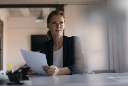 Geschäftsfrau hält Papier am Schreibtisch im Büro - JOSF02992