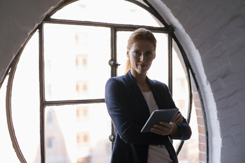 Portrait of confident businesswoman with tablet at the window stock photo