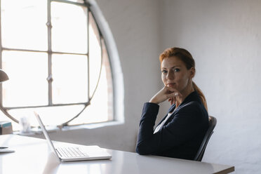 Portrait of businesswoman with laptop sitting at desk in office - JOSF03000