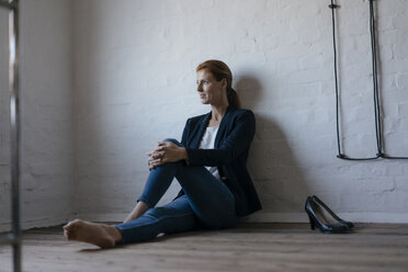 Barefeet businesswoman sitting on floor in office - JOSF03011