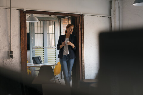 Lächelnde Geschäftsfrau bei einer Kaffeepause im Büro, lizenzfreies Stockfoto