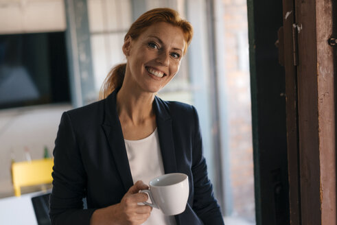 Porträt einer lächelnden Geschäftsfrau in einer Kaffeepause im Büro - JOSF03021