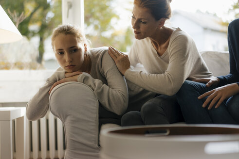Mother consoling sad teenage girl on couch at home - JOSF03056