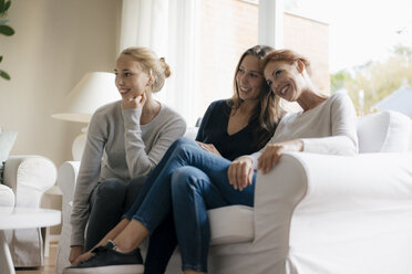Glückliche Mutter mit zwei Mädchen im Teenageralter auf der Couch zu Hause - JOSF03060