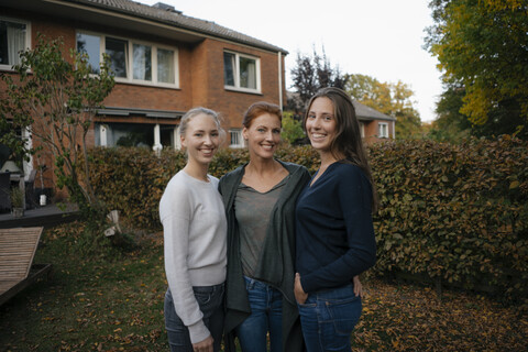 Porträt einer glücklichen Mutter mit zwei Teenager-Mädchen im Garten im Herbst, lizenzfreies Stockfoto