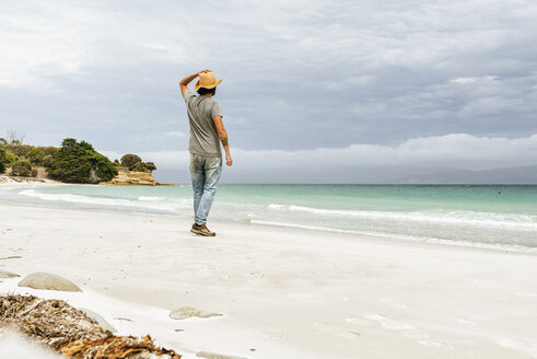 Australien, Tasmanien, Maria Island, Rückenansicht eines Mannes, der am Strand steht und die Aussicht betrachtet - KIJF02173