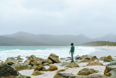 Australia, Tasmania, Freycinet National Park, Wineglass Bay, back view of man standing on the beach - KIJF02198