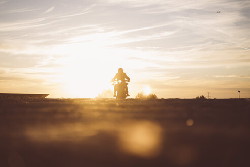 Silhouette eines Mannes auf einem Custum-Motorrad bei Sonnenuntergang - OCMF00223